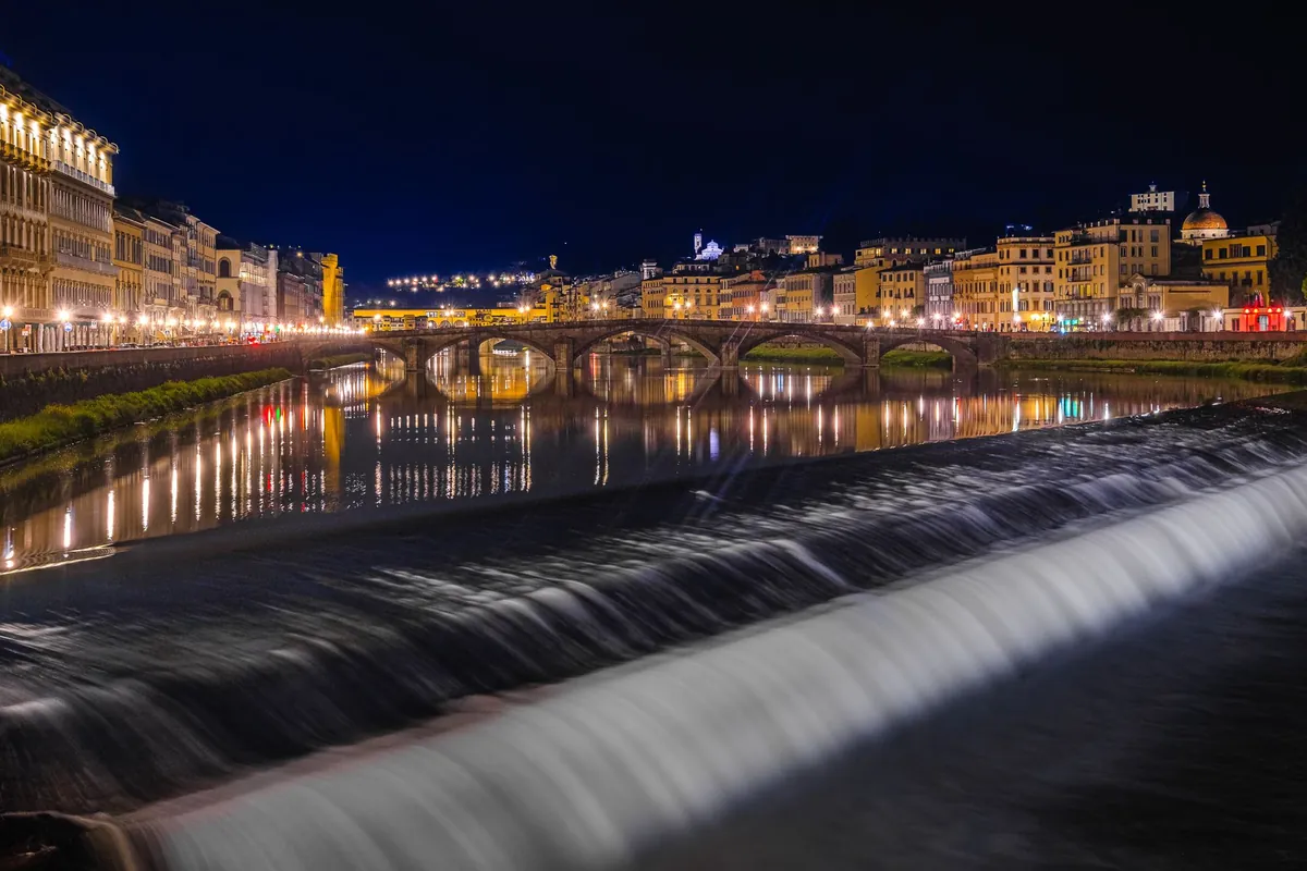 The Arno at night, with the river weir and lit embankments